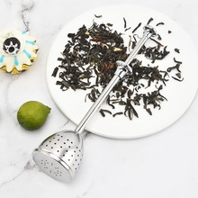 Macro detail of silver 304 stainless steel tea infuser on a marble surface with tea leaves
