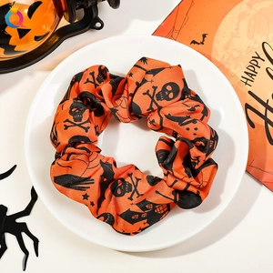 Halloween orange scrunchie with skull patterns displayed on a plate with festive decor