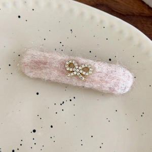 Detailed view of pink felt hair clip with rhinestone bow on decorative ceramic plate