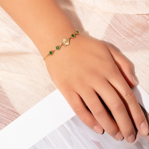 Detail of vintage emerald zircon bracelet with gold sunburst charm and green stars
