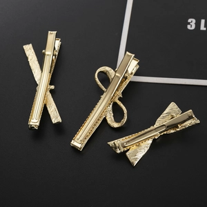 Three textured gold metal bow and X-shaped hair claws on professional black background