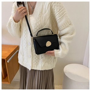 Chic black leather crossbody bag with unique gold geometric clasp on a fashion model