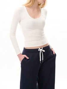 Détail du haut blanc ajusté à col en U avec un pantalon de jogging bleu à cordon de serrage