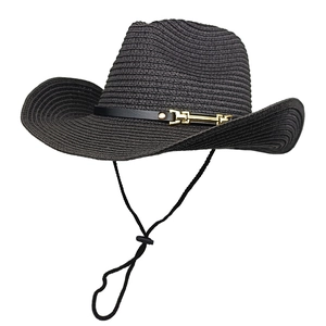 Close-up of black straw cowboy hat featuring golden metal bit buckle and adjustable chin strap