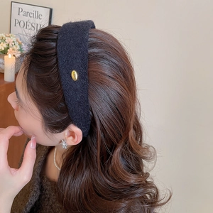 Détail d'un serre-tête en tweed avec emblème doré porté par un mannequin en gros plan