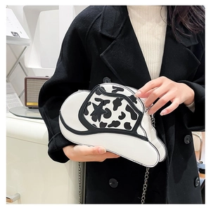 Detail of cow print cowboy hat shaped shoulder bag with star pattern and silver chain