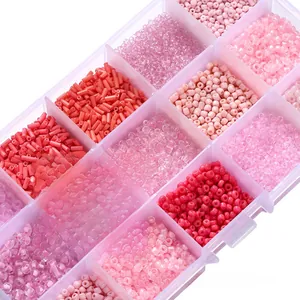 Detail view of pink and red glass seed beads sorted in a 15-grid transparent organizer box