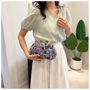 Detail showing vintage floral print handbag with gold metal frame and chain strap