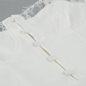 Macro detail of white satin buttons and delicate eyelash lace trim on a long dress