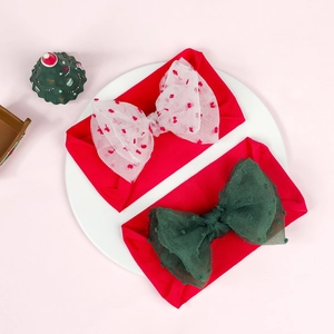 Detail of red Christmas baby headbands featuring mesh bows on a white porcelain plate