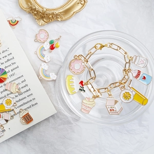 Flat lay of colorful enamel charms featuring donuts and cakes on a gold chain bracelet