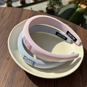 Detailed view of padded sponge headbands in pastel pink and blue with paperclip accents