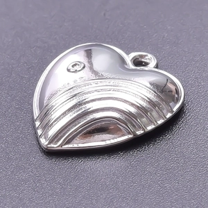 Macro shot of 18k gold plated heart pendant with textured ridges and polished steel finish