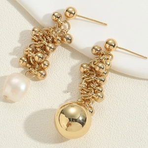 Macro detail of Baroque pearl and mirror gold ball on elegant asymmetric earrings