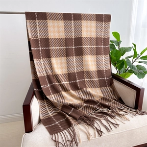 Detail eines karierten Pashmina-Schals mit Fransen auf einem beigen Sessel