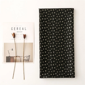 Detail of black cotton scarf featuring golden foil sprout patterns and rolled edges
