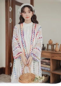 Dettaglio del cardigan in pizzo bianco con ricami a motivi geometrici colorati