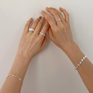 Close-up of minimalist 925 silver rings and heart bracelets set on model hand