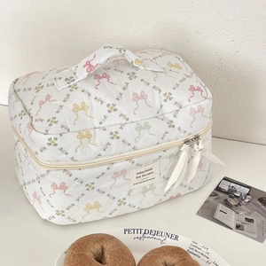 Détail de la trousse de maquillage matelassée aux motifs floraux et nœuds élégants