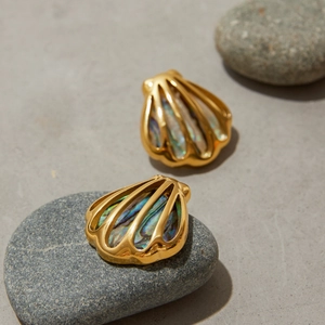 Detailaufnahme von muschelförmigen Goldohrringen mit Abalone-Inlay auf Kiesel