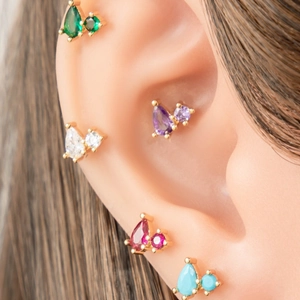 Golden cartilage studs featuring teardrop zircons in diverse colors on a model ear