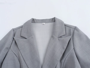 Détail du col d'une veste grise à carreaux avec l'etiquette taille S sur tissu doux