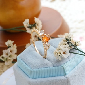 Vista macro de un anillo de plata 925 bañada en oro con granate naranja y cristal blanco