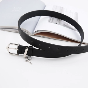 Vintage black leather belt with silver metal buckle and cross pendant on magazine background