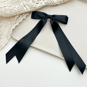 Dettaglio del fiocco in raso nero con lunghi nastri su un vassoio bianco decorato