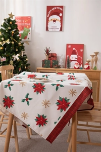 Detail of Christmas tablecloth with red poinsettia, holly berries and plaid border edges