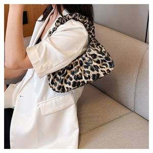 Fashionable leopard print pleated cloud shoulder bag worn by model in white suit