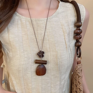 Detail of vintage wooden flower and translucent resin oval pendant on long necklace