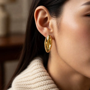 Detail of marquise-cut amber crystal earring with gold textured border on a model