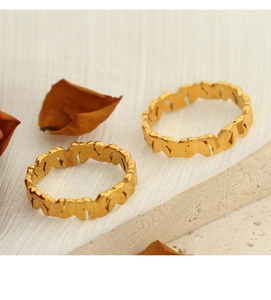 Detail of two gold-plated butterfly rings with hollow design on white fabric and stone