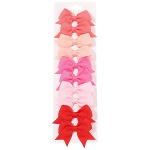 Dettaglio di dieci fermagli per capelli con fiocco in nastro grosgrain rosso e rosa per bimba
