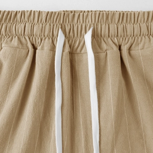 Dettaglio dei pantaloni in lino cachi con vita elastica e coulisse bianca uomo