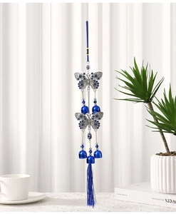 Detail of blue evil eye butterfly wind chime with silver metal bells and tassel