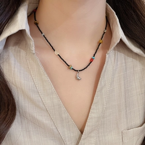 Detail of beaded ethnic necklace with natural stones and silver snail pendant worn on neck