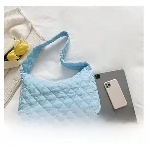 Detailed top view of light blue quilted tote bag on white textured cloth surface