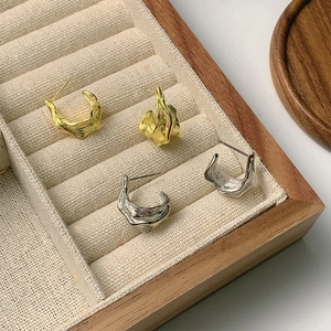 Detailed close-up of irregular foil texture stud earrings in gold and silver finishes