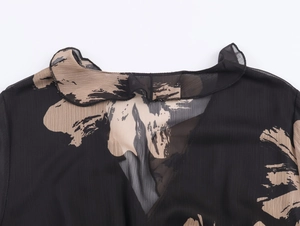 Close-up of ruffled neckline and pussy bow detail on beige brushstroke chiffon dress