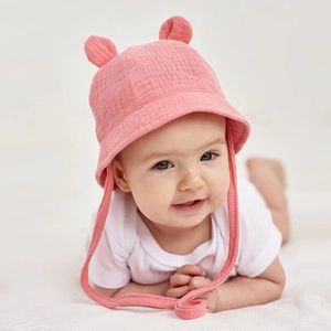 Detail of pink cotton baby sun hat with bunny ears and adjustable chin strap on an infant