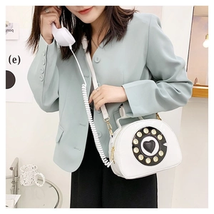 Unique telephone-shaped crossbody bag in white faux leather shown by a model