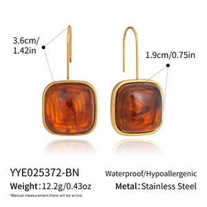 Détail de boucles d'oreilles carrées en résine ambrée avec crochets en acier et tailles