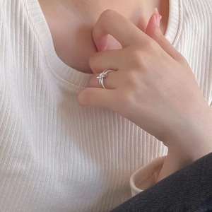 Close-up of minimalist silver knot ring worn on index finger with sleek polished finish