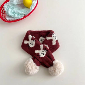 Detail of burgundy kids knit scarf with white rabbit pattern and beige pom poms