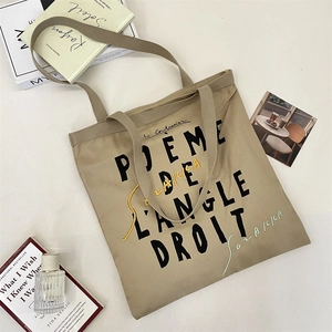 Detail of khaki canvas tote bag featuring black French poetry text and artistic lines