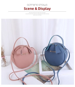 Detail view of pink and blue round crossbody bags with pebbled leather texture and metal logo