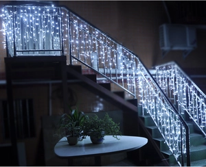 Cold white LED icicle curtain lights hanging on metal stairs for festive outdoor decoration