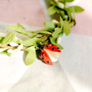 Charming ladybug brooch with red enamel and opal stone on delicate green leaf